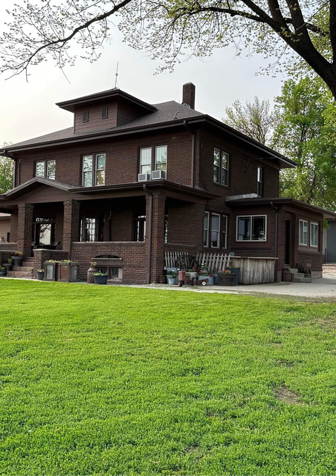 A two-story brick home with a clean lawn and trimmed landscaping