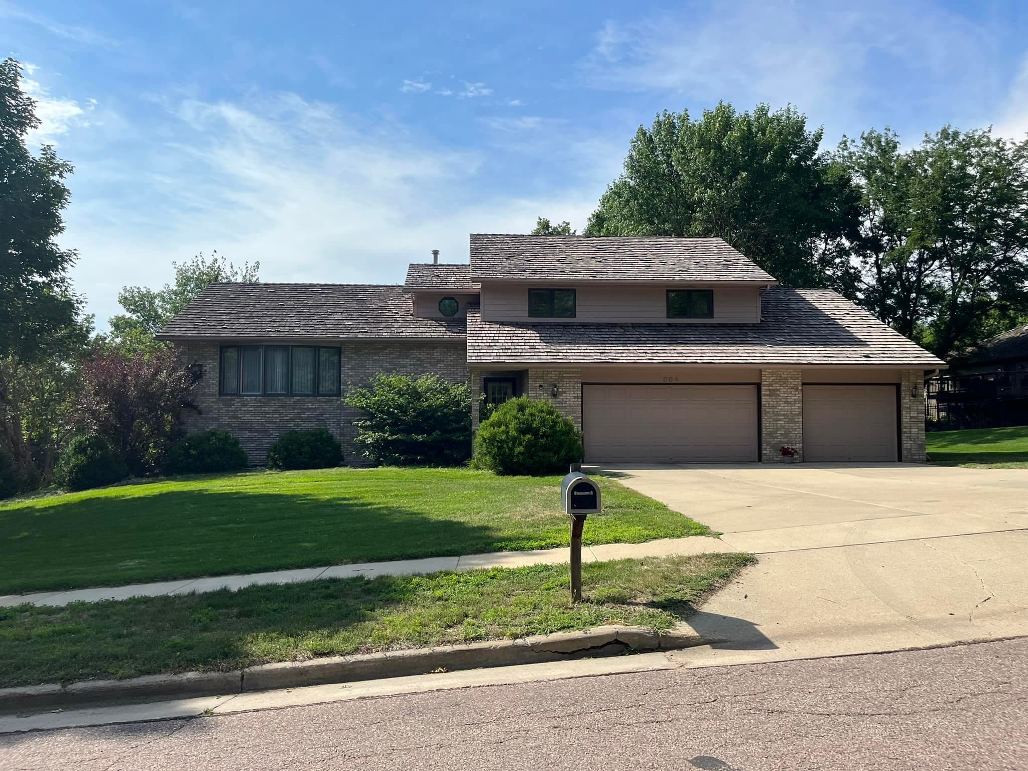 A home with a cedar shake roof and a freshly kept yard