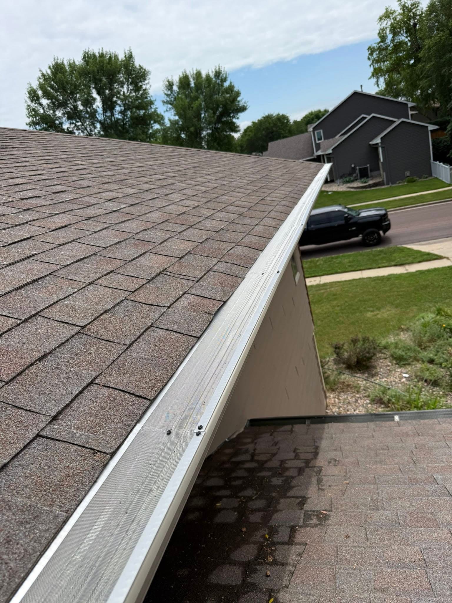 A rooftop view down a freshly guarded gutter line, new gutter guards running the length of the eave